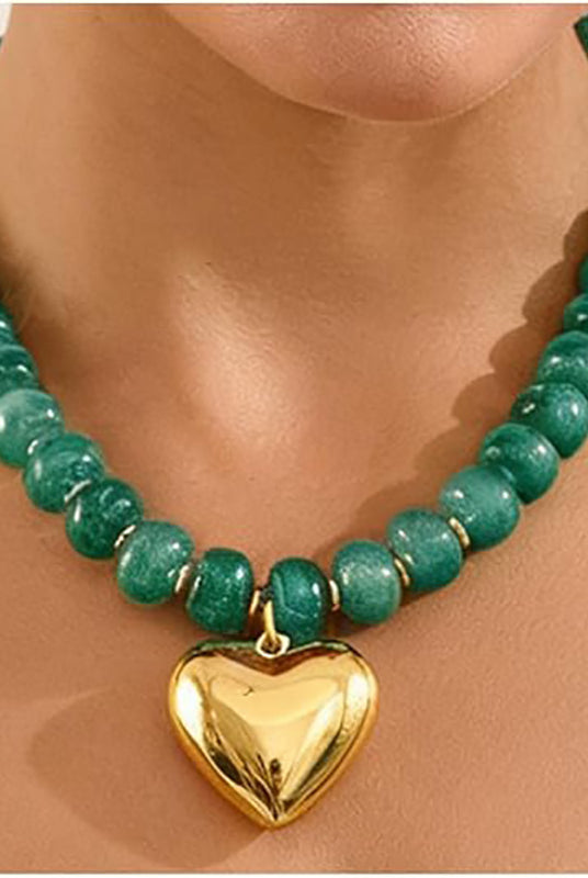 A green beaded necklace with a shiny gold heart-shaped pendant, shown on a model's neck.