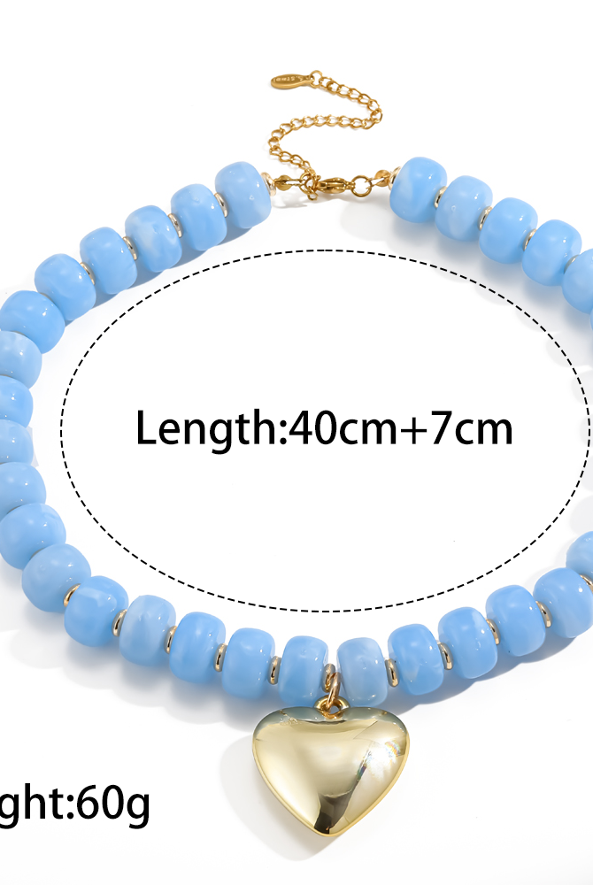 A light blue beaded necklace with a gold heart pendant and chain clasp, shown on a white background with printed text indicating length and weight.