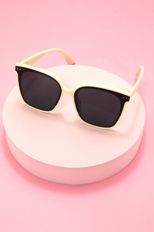 Sunglasses with beige frame and black lenses on a pink background