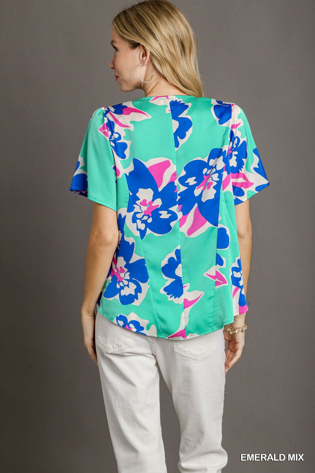 Woman wearing a colorful floral blouse with a gray background