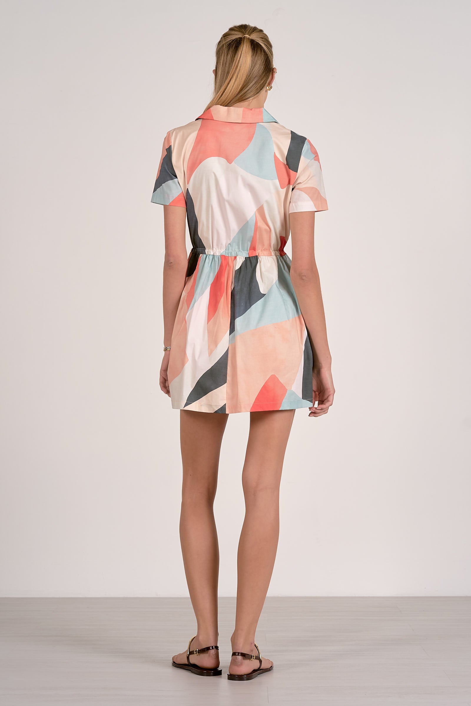 Woman wearing a colorful geometric patterned dress on a plain background