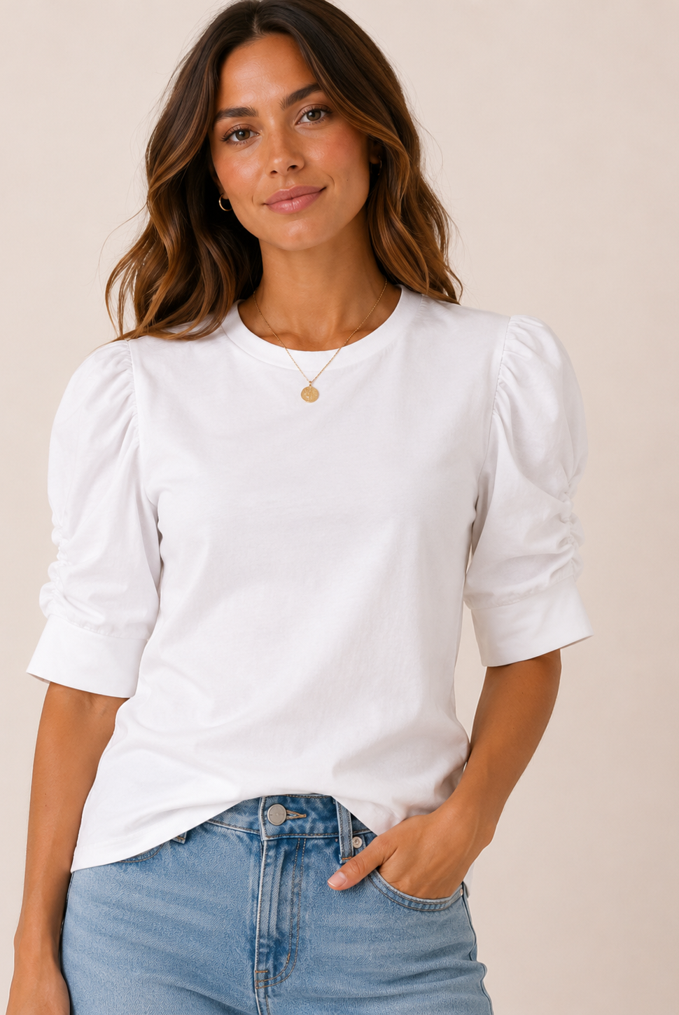 Woman wearing a white blouse with puffed sleeves and blue jeans on a beige background