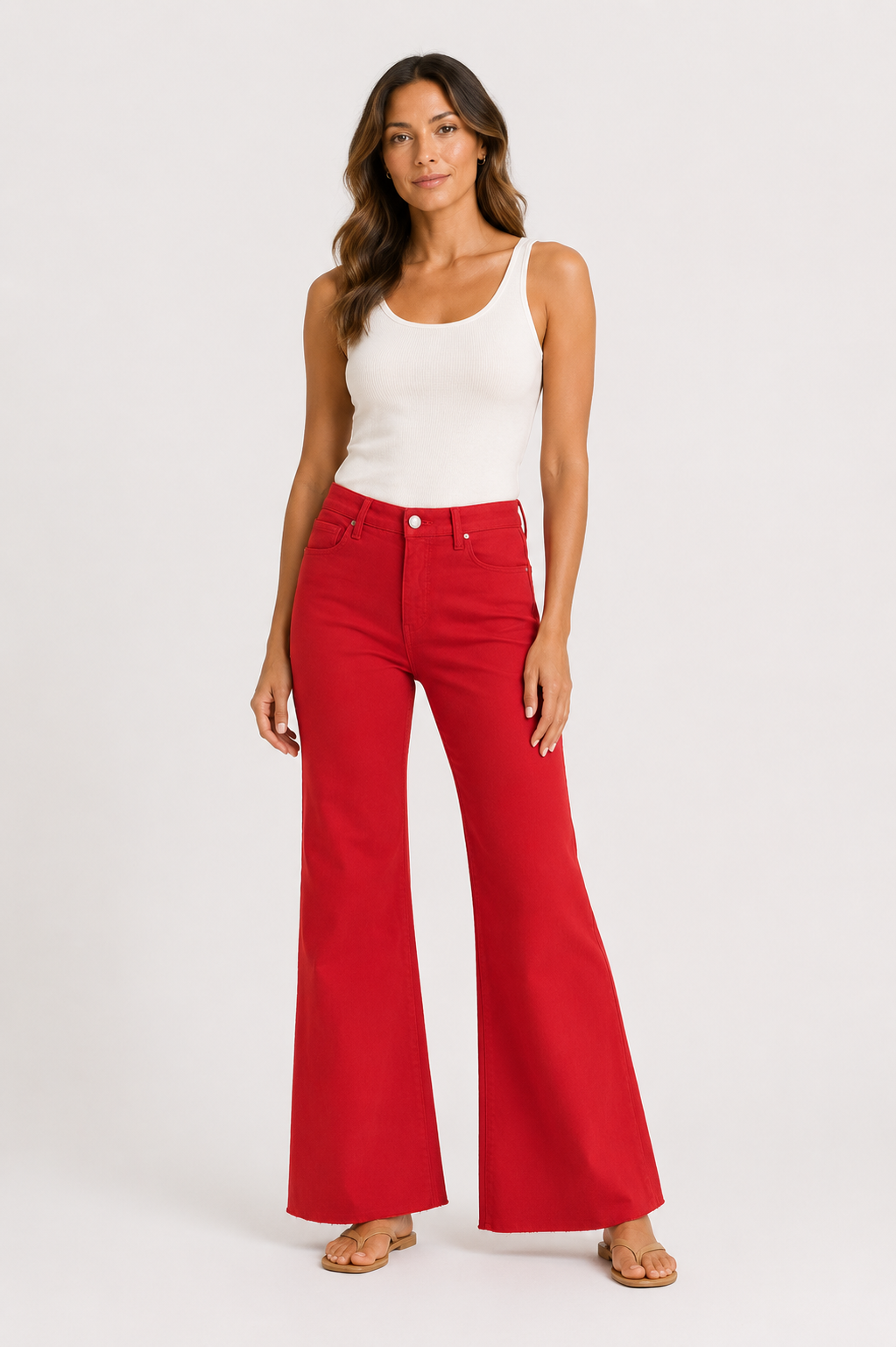 Woman wearing a white tank top and red flared pants on a white background