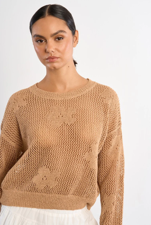 Woman wearing a beige knitted sweater against a white background