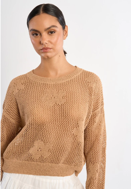 Woman wearing a beige knitted sweater against a white background