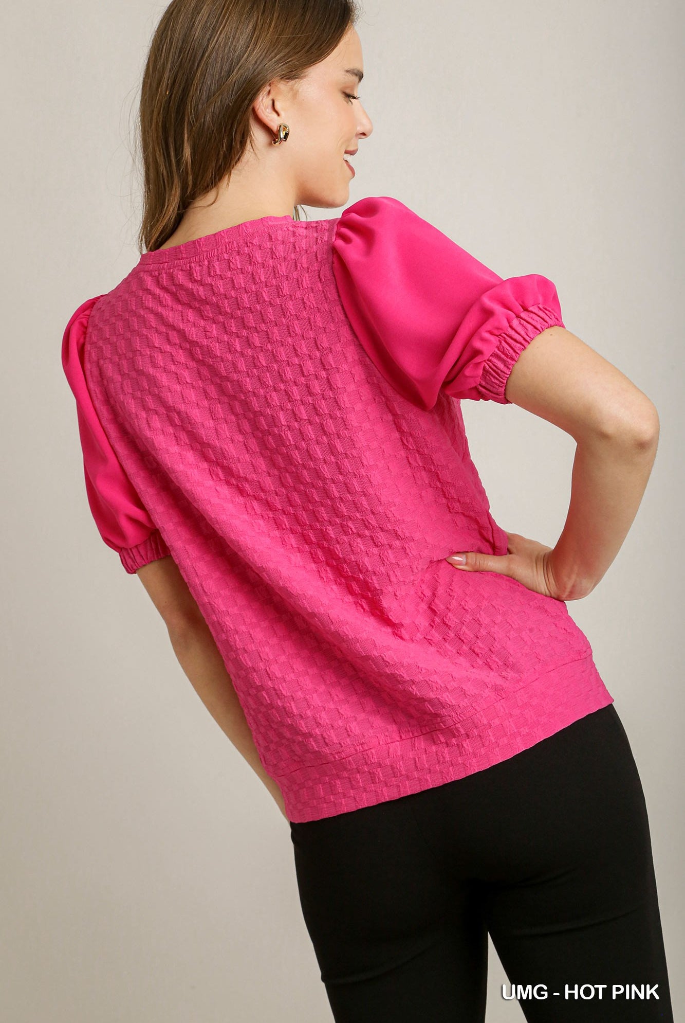 Woman wearing a hot pink textured top against a neutral background