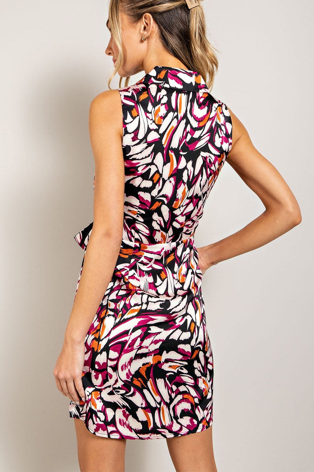 Woman wearing a colorful patterned dress against a plain background