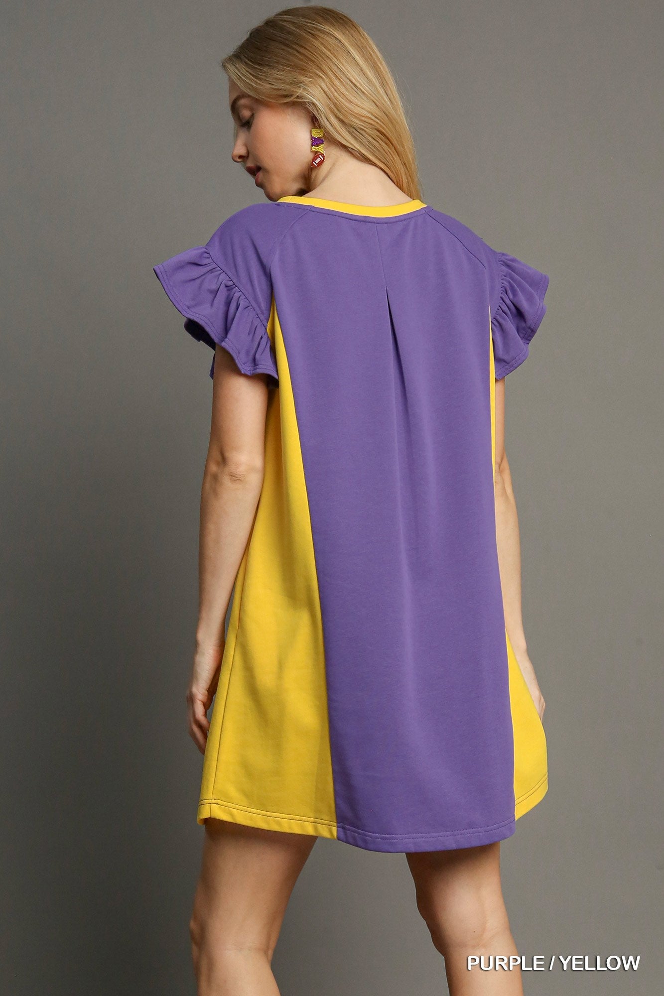 Woman wearing a purple and yellow dress against a gray background