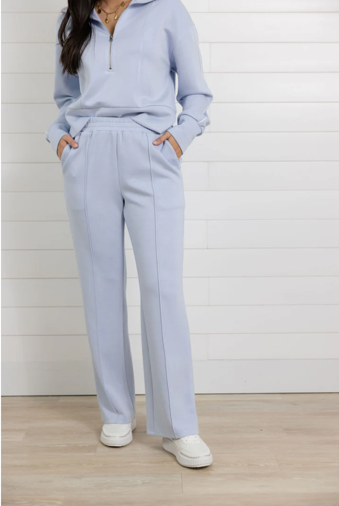 Person wearing a light blue outfit with white sneakers on a wooden floor.