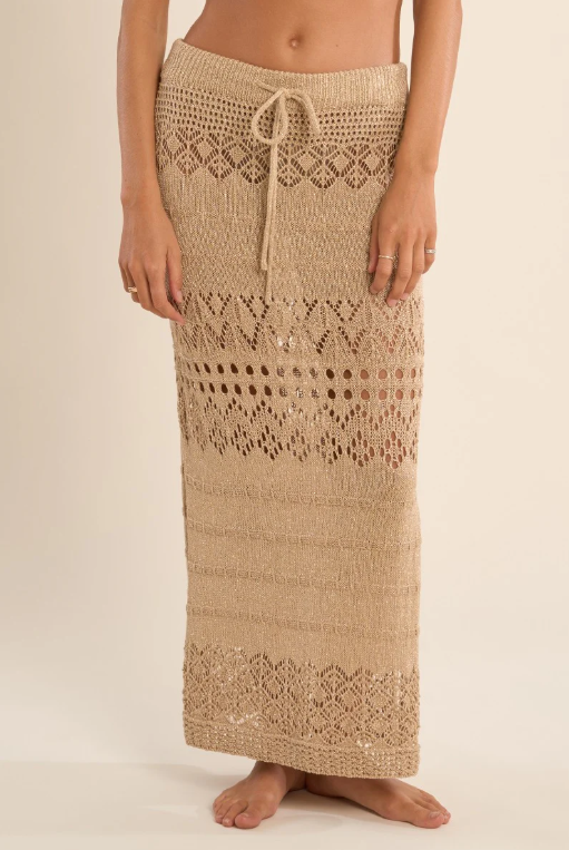 Gold crochet skirt worn by a person on a beige background
