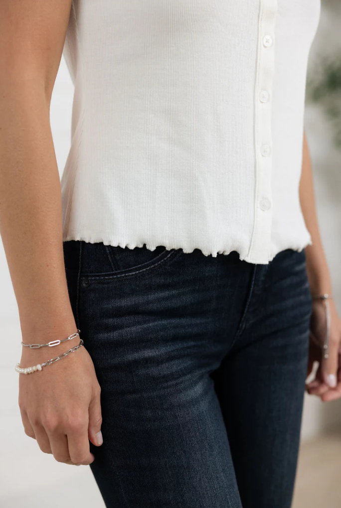 Person wearing a white blouse and dark jeans with a blurred background