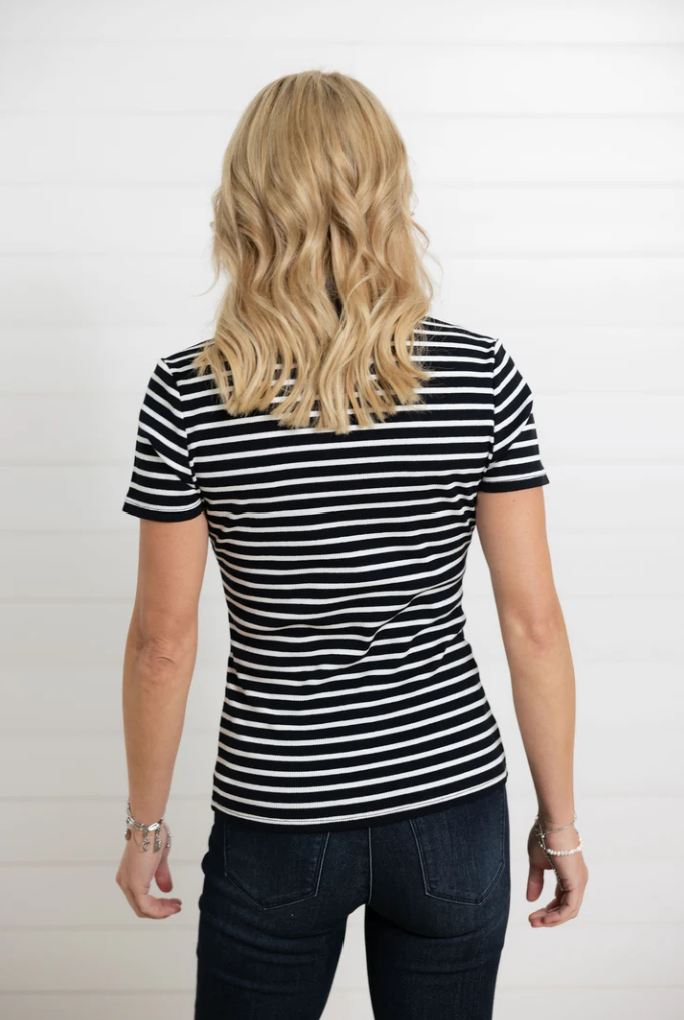 Person wearing a black and white striped shirt and dark jeans on a plain background