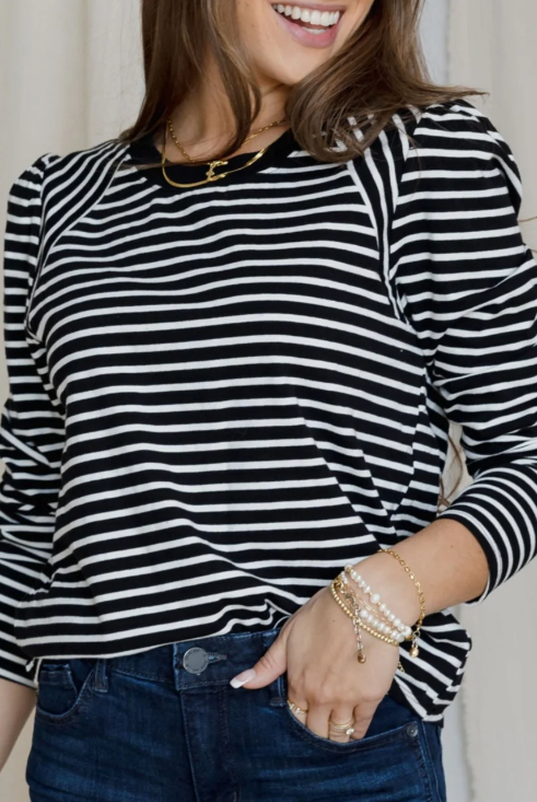 Woman wearing a black and white striped long-sleeve top with a plain background