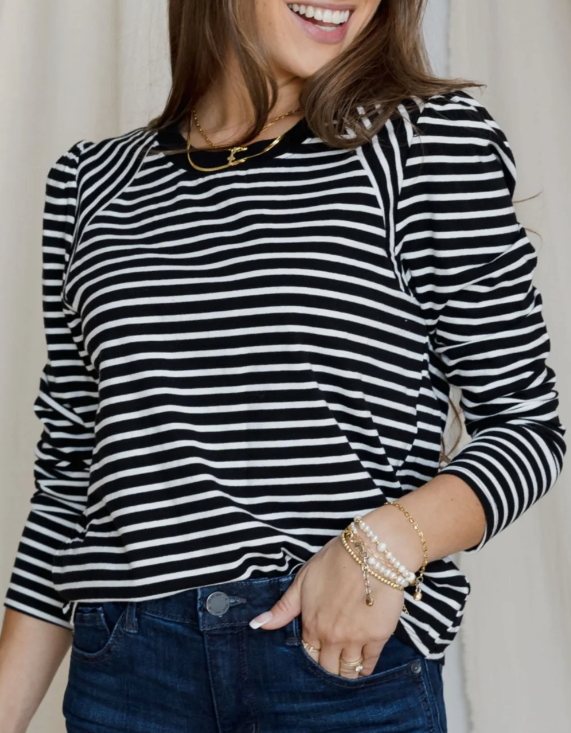 Woman wearing a black and white striped long-sleeve top with a plain background