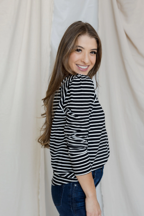 Woman wearing a black and white striped shirt against a plain background