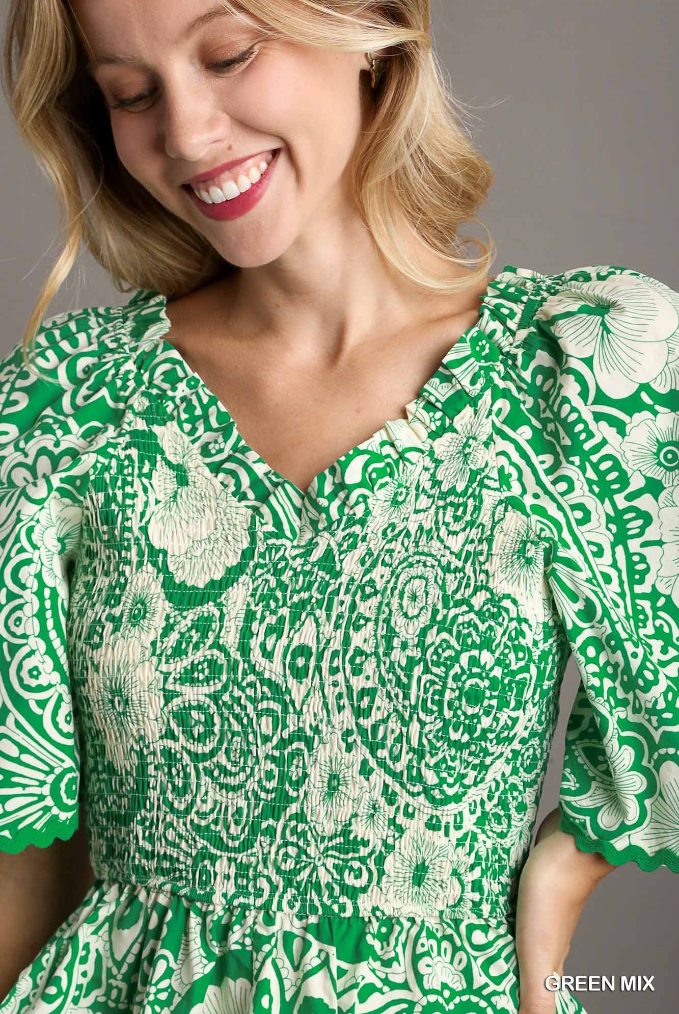 Woman wearing a green and white patterned dress against a gray background