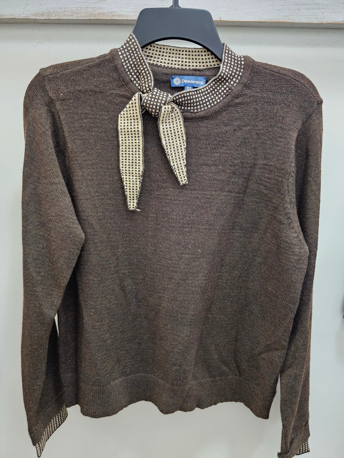 Heather dark brown sweater with oatmeal contrast tie neckline on hanger