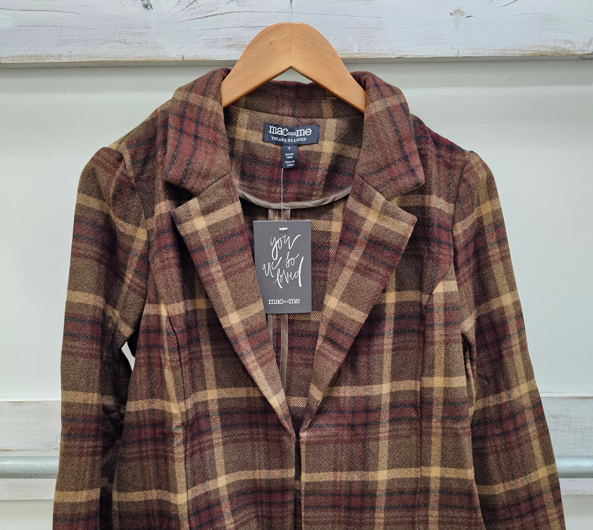 A women's plaid blazer jacket from the brand Chloé, hanging on a wooden hanger against a white paneled wall. The jacket features a brown, beige, and burgundy tartan pattern with notched lapels and front flap pockets.