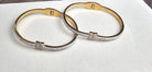 Two gold bangles with diamond accents on a white surface