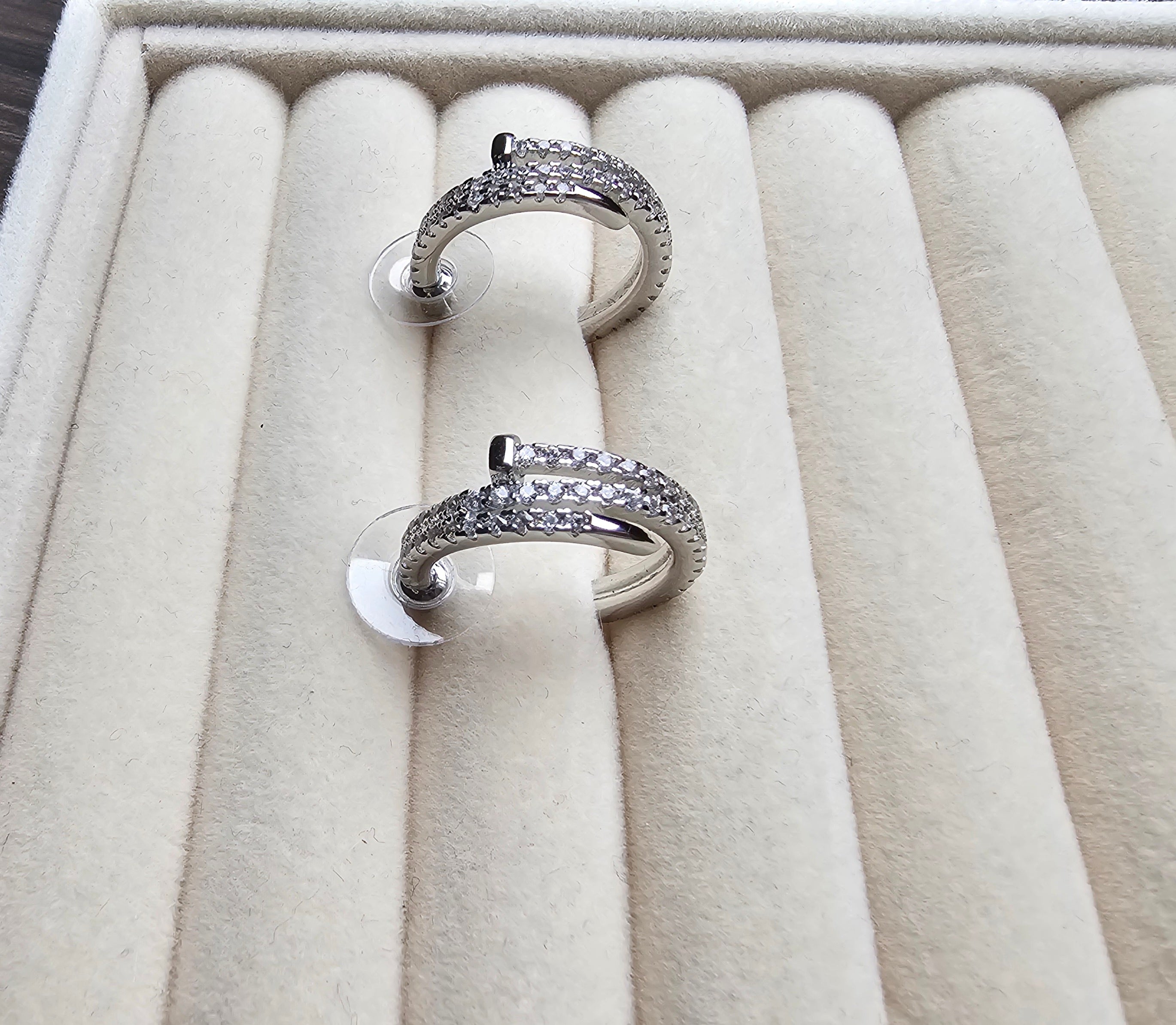 Two silver rings with gemstones on a beige jewelry box
