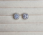 Pair of silver stud earrings with clear gemstones on a light gray surface