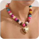 Colorful beaded necklace with a gold heart pendant on a person's neck.