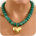 A green beaded necklace with a shiny gold heart-shaped pendant, shown on a model's neck.