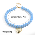 A light blue beaded necklace with a gold heart pendant and chain clasp, shown on a white background with printed text indicating length and weight.