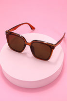 Sunglasses with brown lenses and red-orange frame on a white background