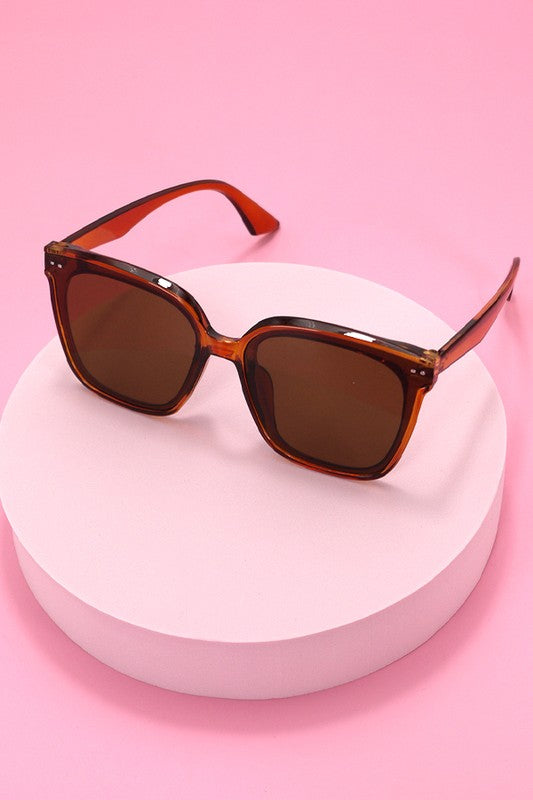 Sunglasses with brown lenses and red-orange frame on a white background