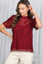 Woman wearing a red lace top against a white background
