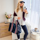 Woman taking a selfie in a living room holding a striped bag.