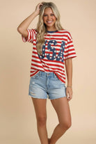Woman wearing a red, white, and blue 'USA' t-shirt with denim shorts on a beige background