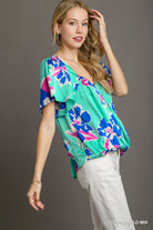 Woman wearing a colorful floral top with a gray background