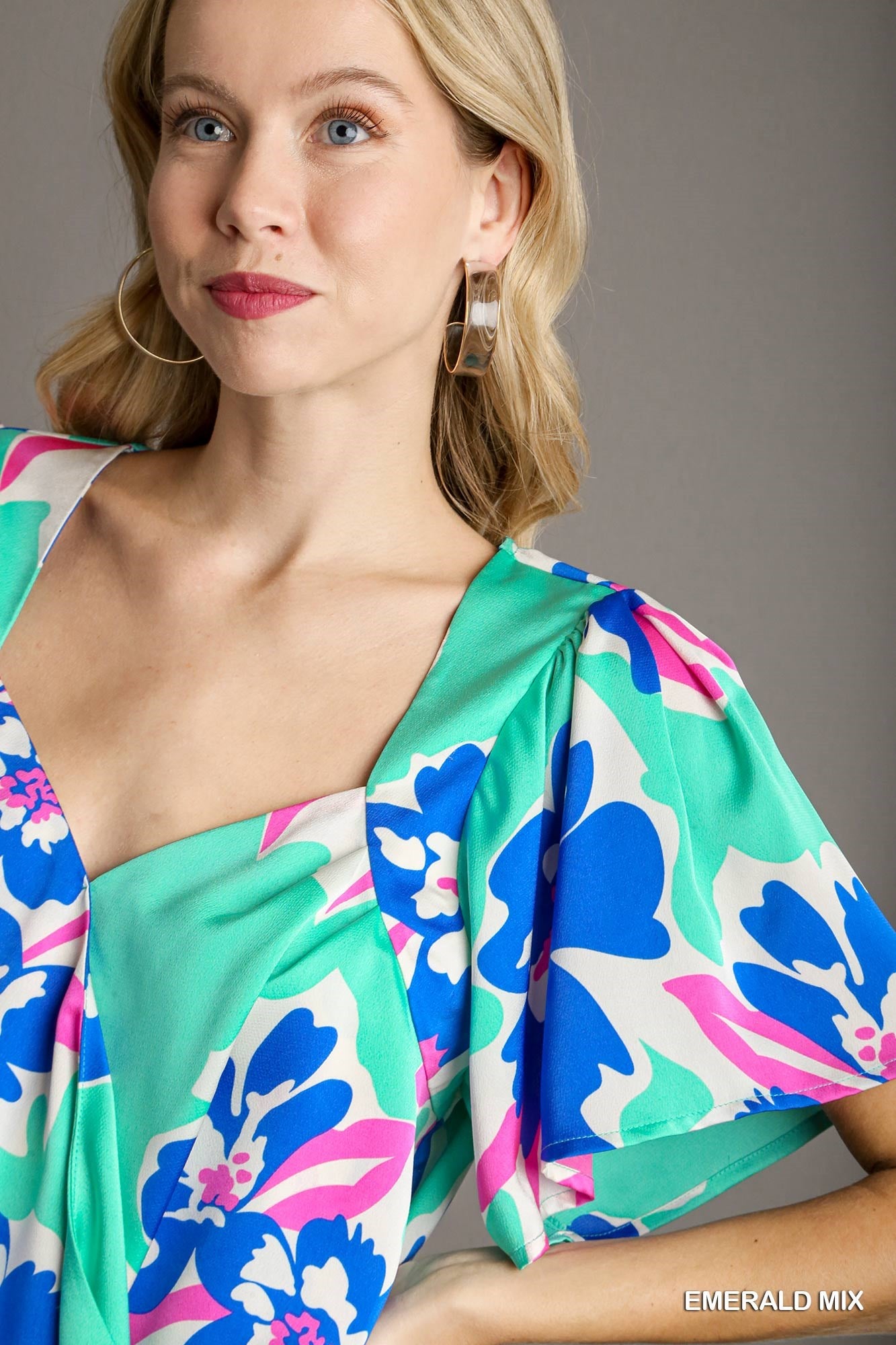 Woman wearing a colorful floral blouse against a gray background
