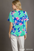 Woman wearing a colorful floral blouse with a gray background