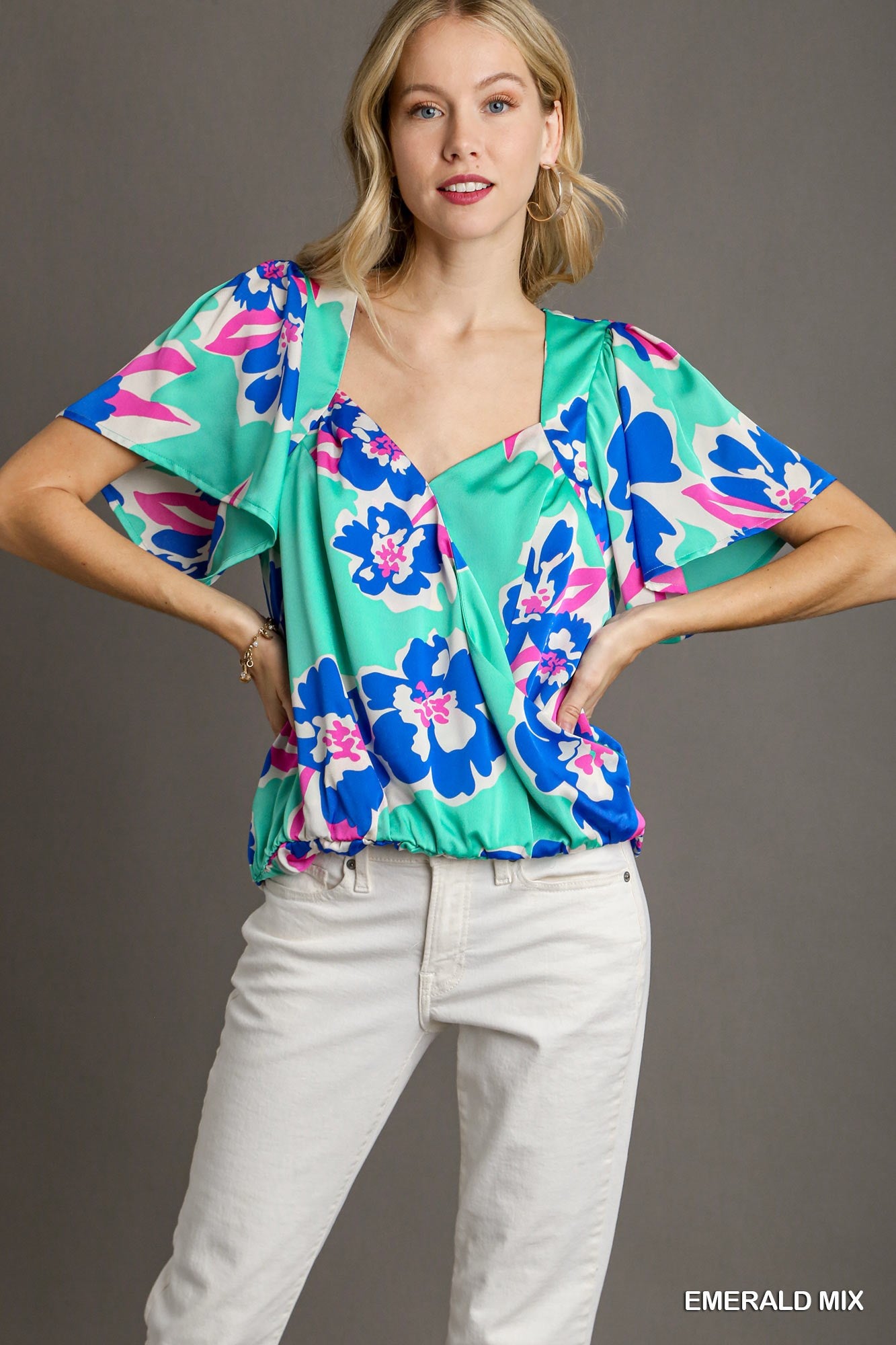 Woman wearing a colorful floral blouse with a gray background