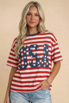 Woman wearing a red, white, and blue 'USA' graphic t-shirt against a beige background