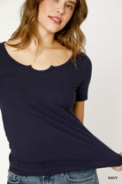 Woman wearing a navy blue top with a scalloped neckline on a white background