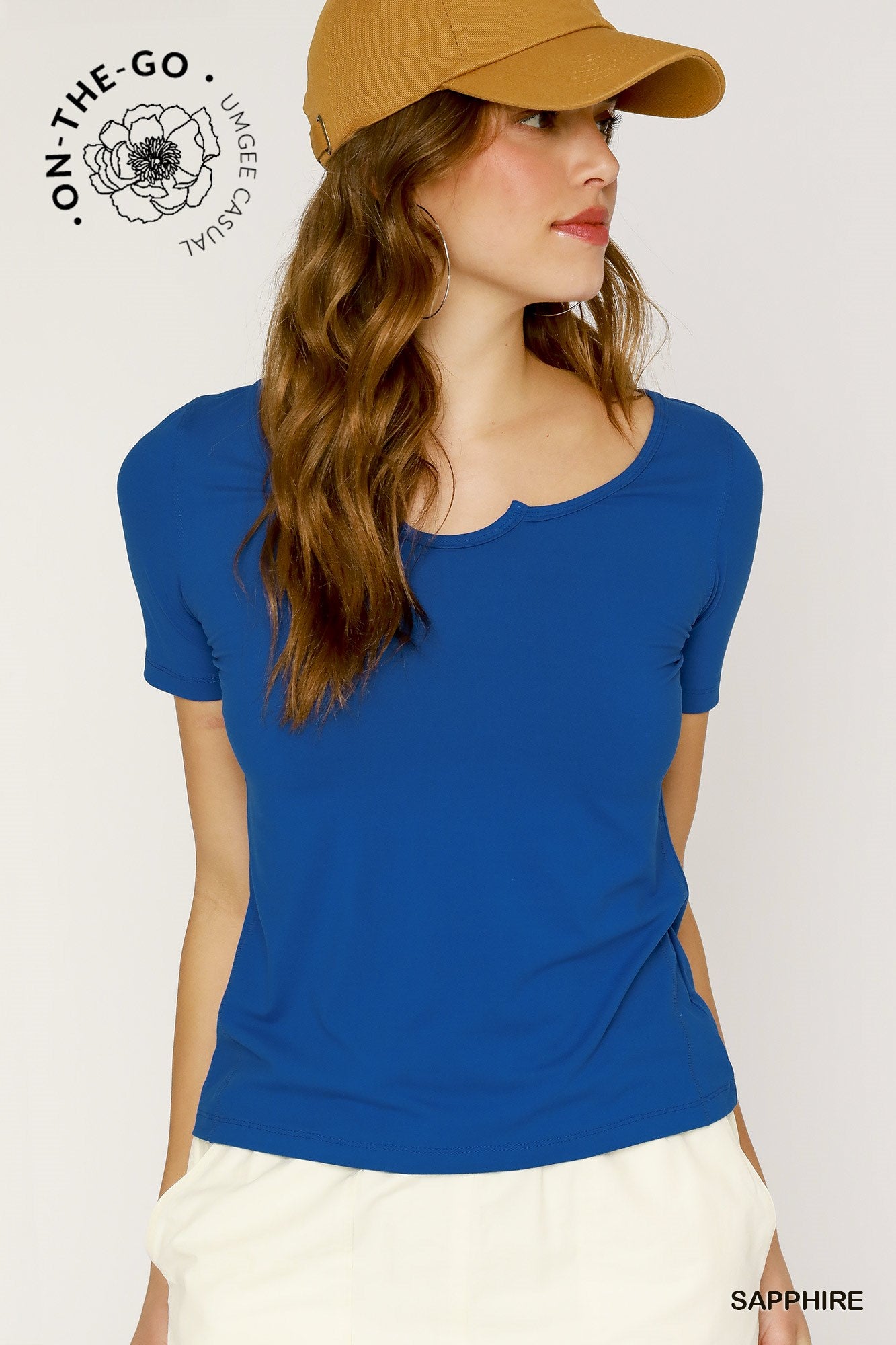 Woman wearing a blue shirt and tan cap on a plain background
