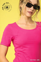 Woman wearing a pink shirt and sunglasses with a yellow background