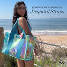 Woman holding a transparent beach bag with turquoise straps on a beach.
