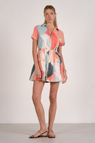 Woman wearing a colorful patterned dress on a plain background