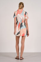 Woman wearing a colorful geometric patterned dress on a plain background