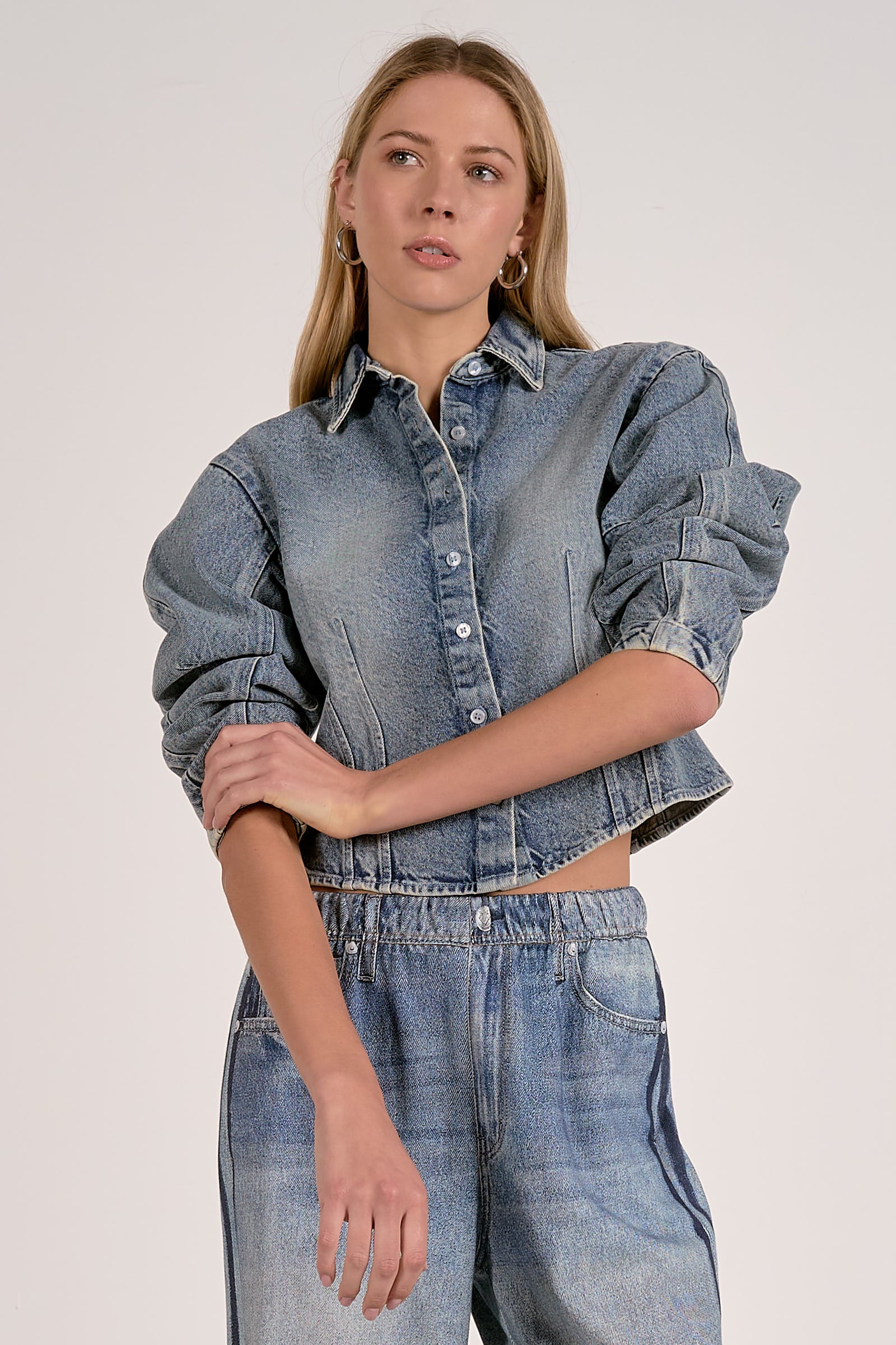 Person wearing a denim jacket and jeans on a plain background