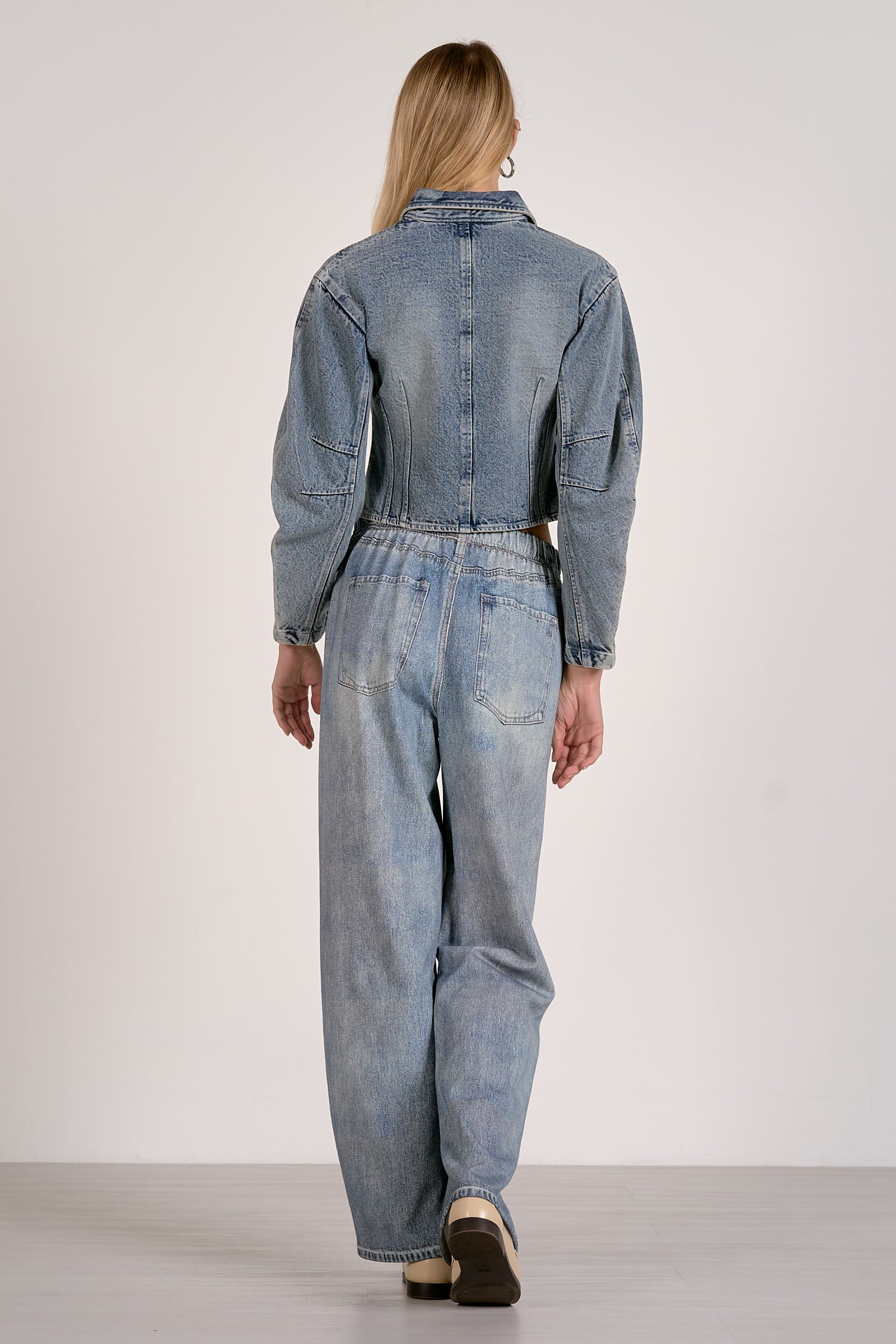 Person wearing a denim jumpsuit on a plain background