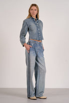 Woman wearing a denim outfit with wide-leg jeans on a plain background