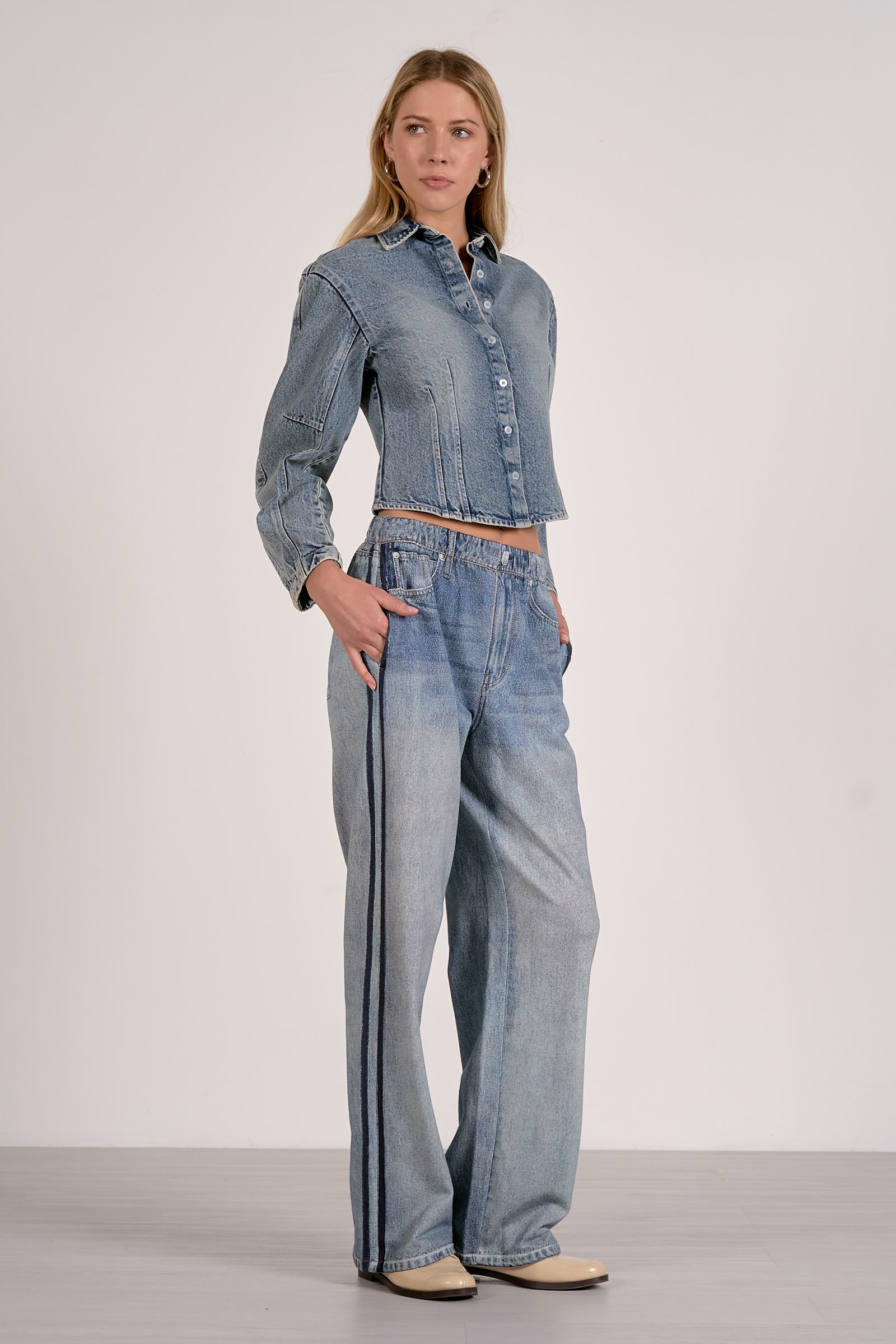 Woman wearing a denim outfit with wide-leg jeans on a plain background