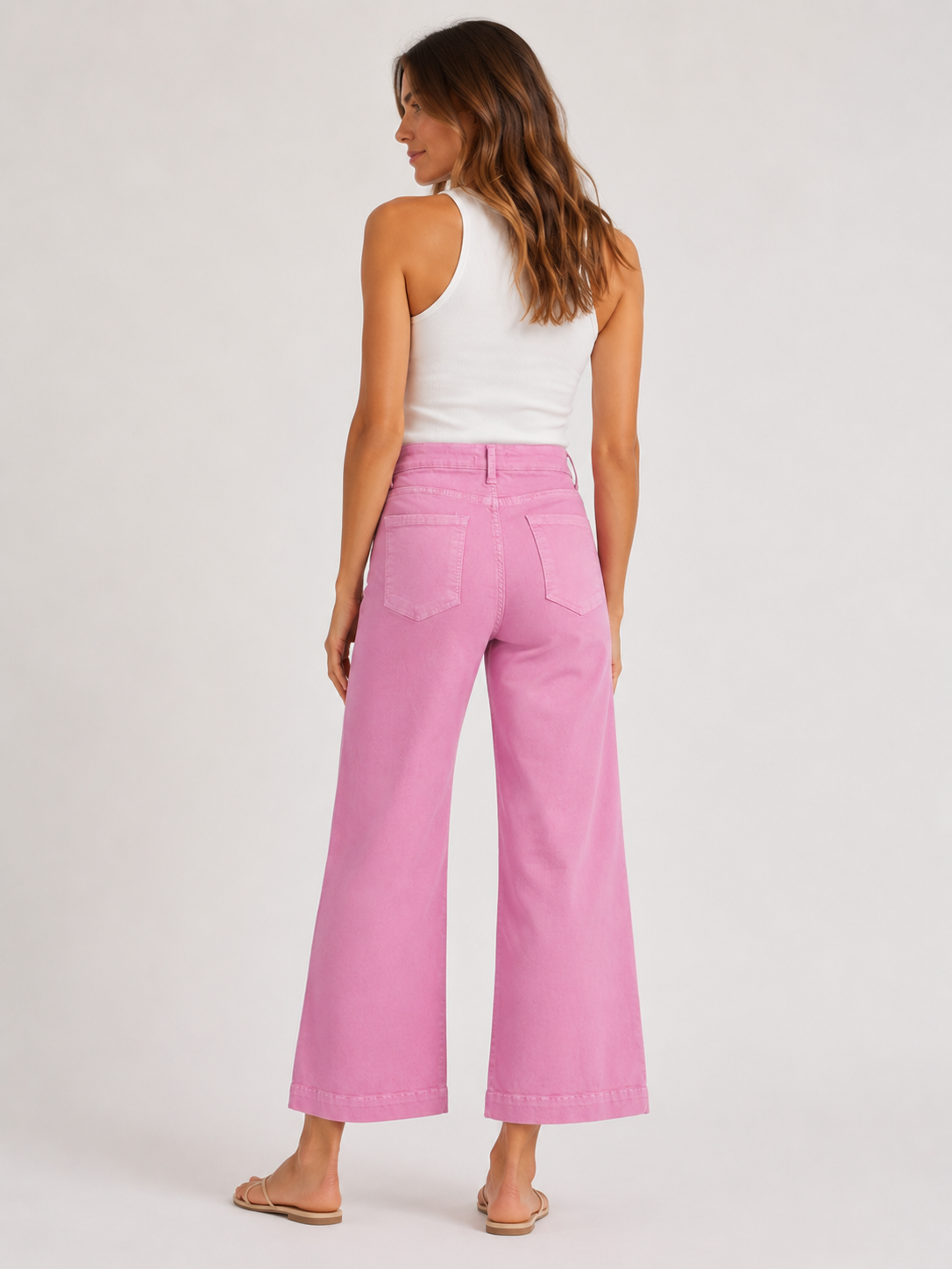 Woman wearing pink pants and a white top on a plain background