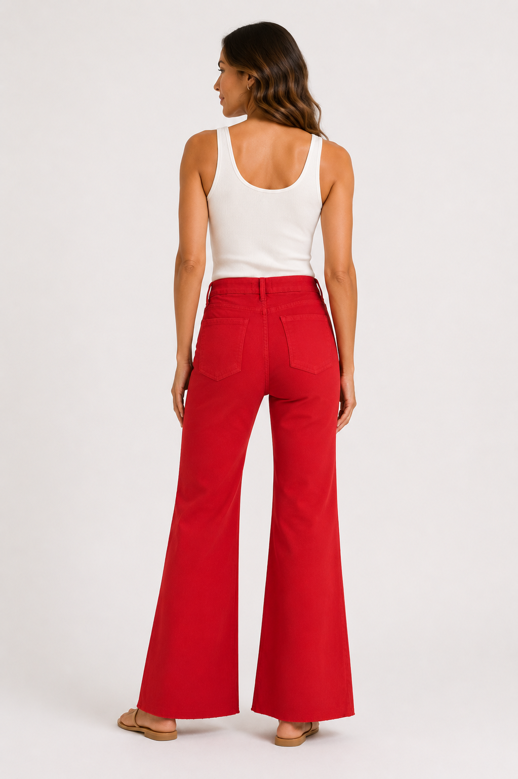 Woman wearing red flared pants and a white tank top on a white background